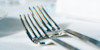 Two silver forks that have been laid out on the restaurant table