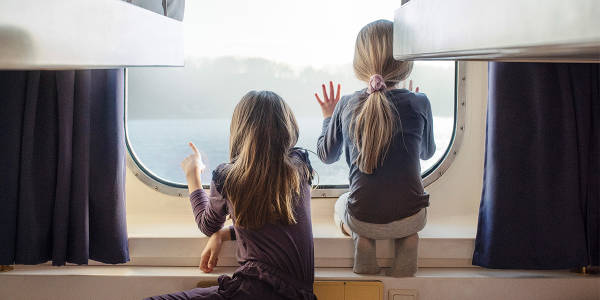 Två flickor tittar ut genom fönstret från hytten