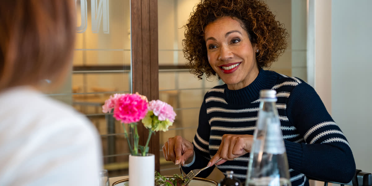 Frau lächelt und isst im Restaurant an Bord der DFDS-Fähre Amsterdam-Newcastle 