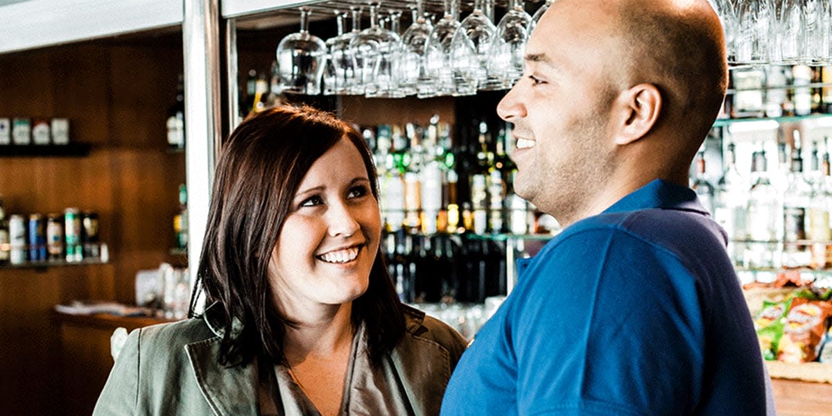Uśmiechnięta kobieta i mężczyzna w barze, w tle widać kieliszki