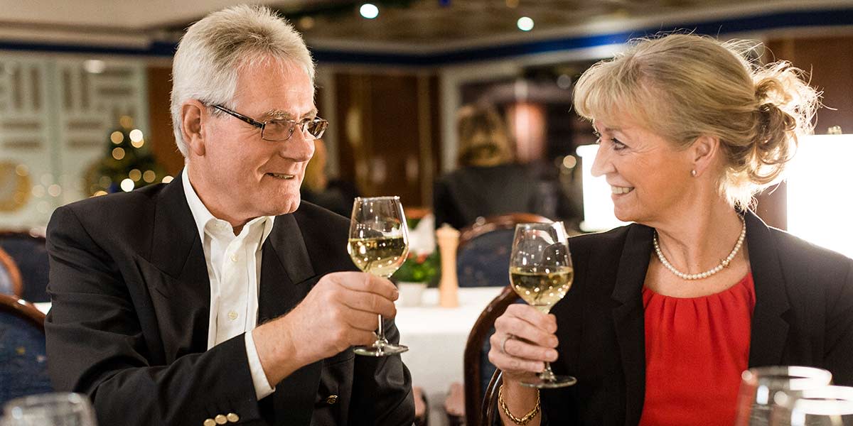 Älteres Paar stößt mit einem Weißweinglas ein