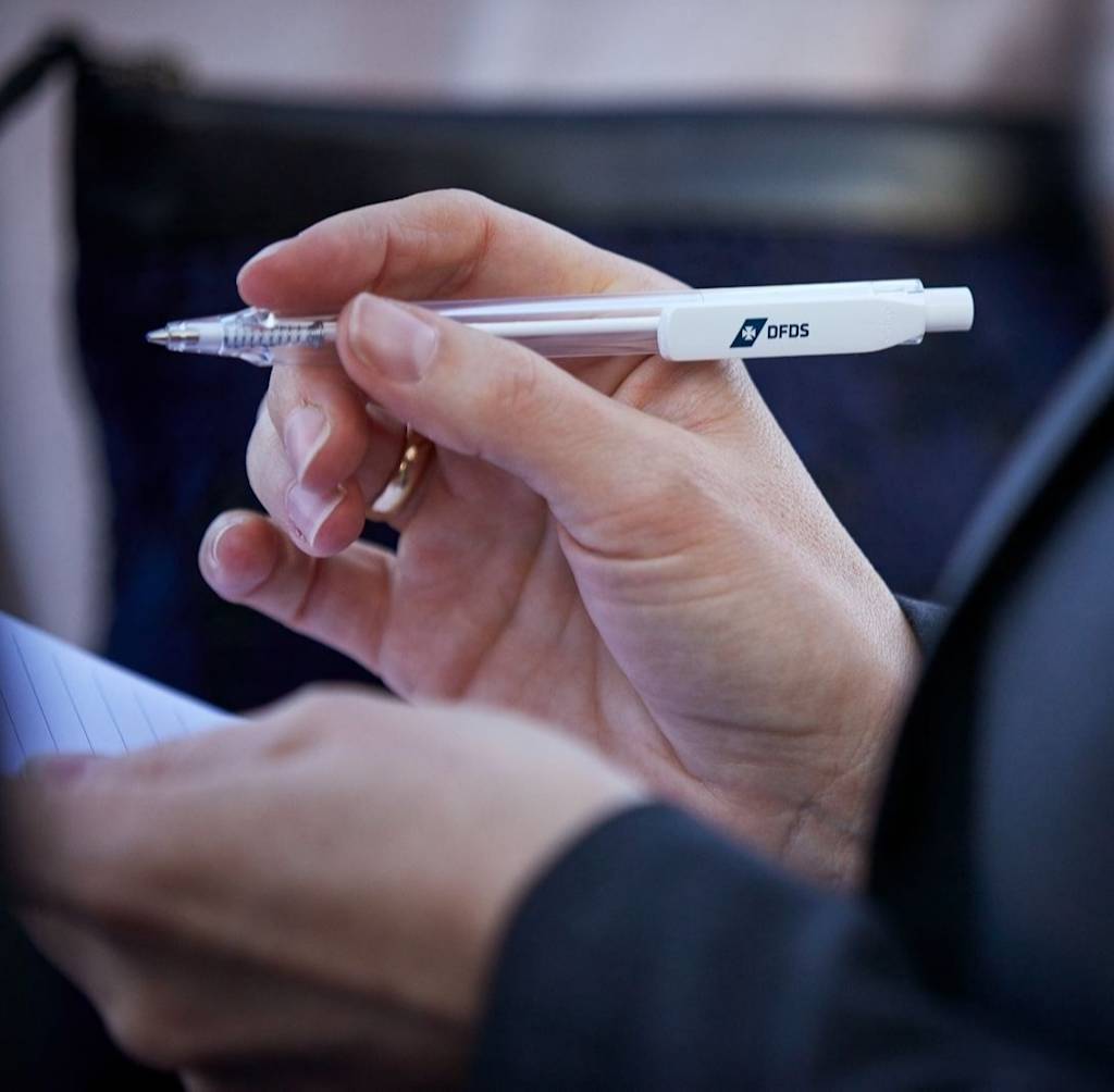 Photo of a DFDS employee taking notes with a pen on a paper notepad DFDS-CON 1083 Conference 2018-medium