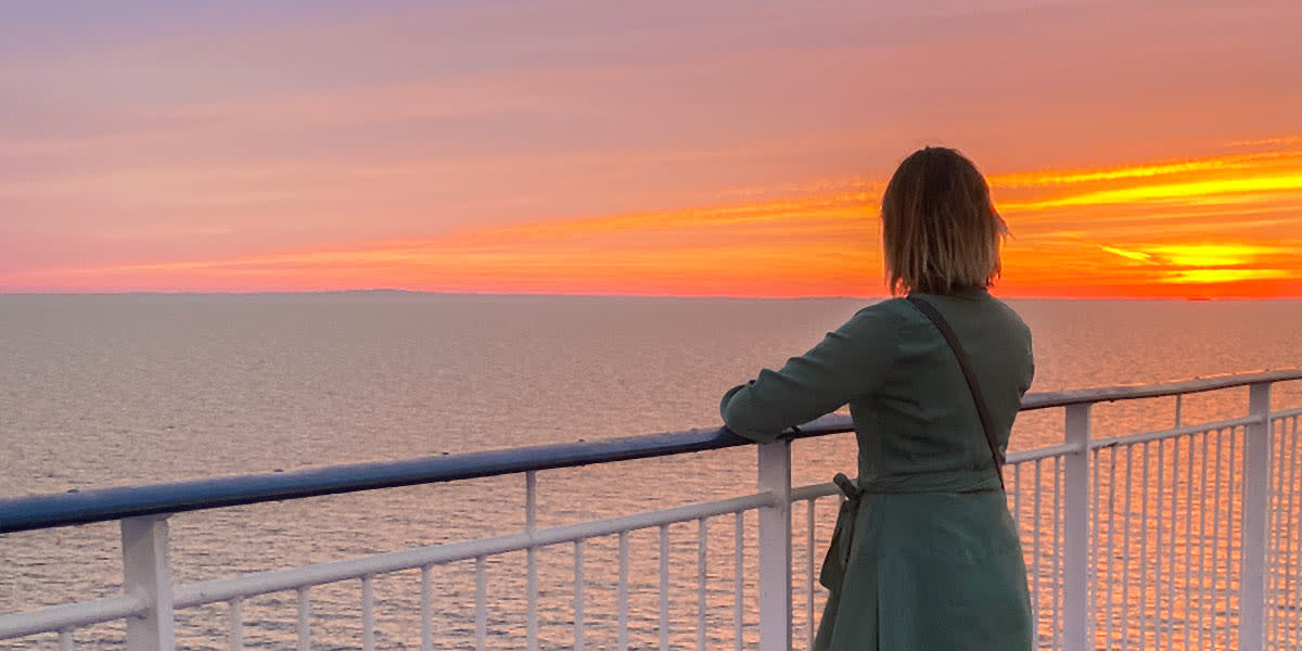 Woman looking at sunset on board Hero