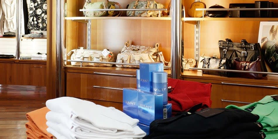 Ubrania, perfumy i torebki na półkach w tle w sklepie bezcłowym
