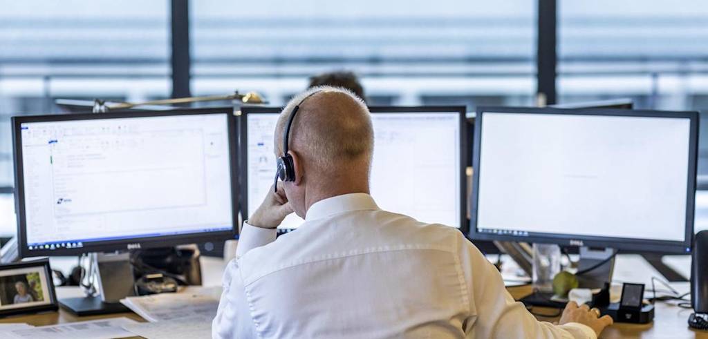 DFDS employee seen from the back, behind desk with three monitors, with headphones on DFDS EmployeeBrand OfficeJobs Page, First Block v1, Text & Media Content