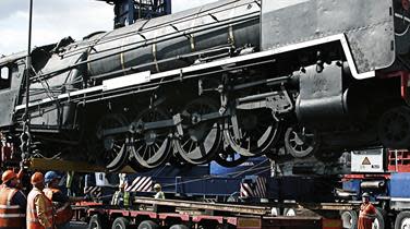 A train locomotive being loaded onto a truck by DFDS employees