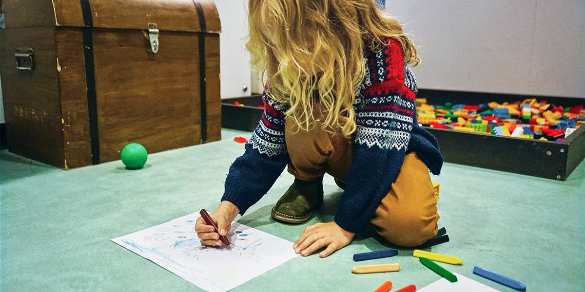 Mädchen malt ein bild mit Buntschtiften in kids club