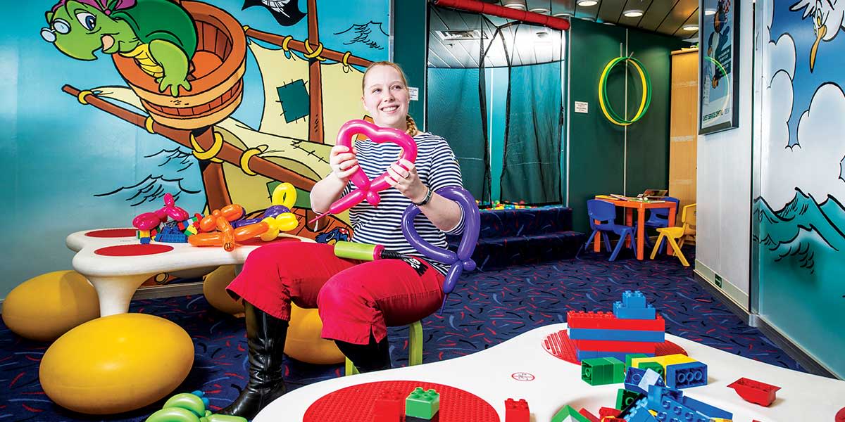 Animatorka siedzi na krześle w Kids clubie i tworzy figury z balonów