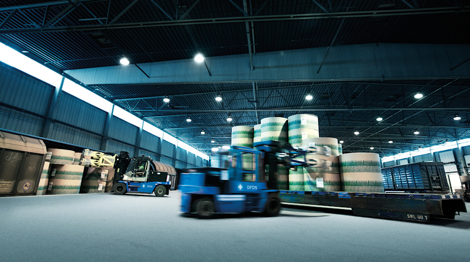 Multiple forklifts loading forest products in a DFDS Logistics warehouse