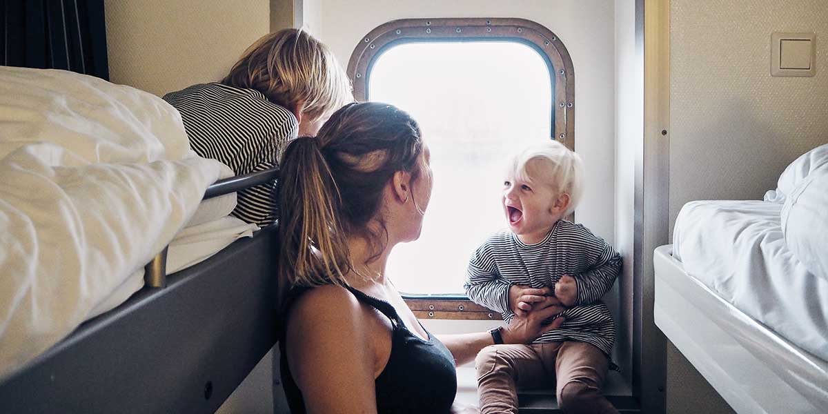 Matka z dziećmi patrzy przez okno w kabinie na pokładzie promu DFDS