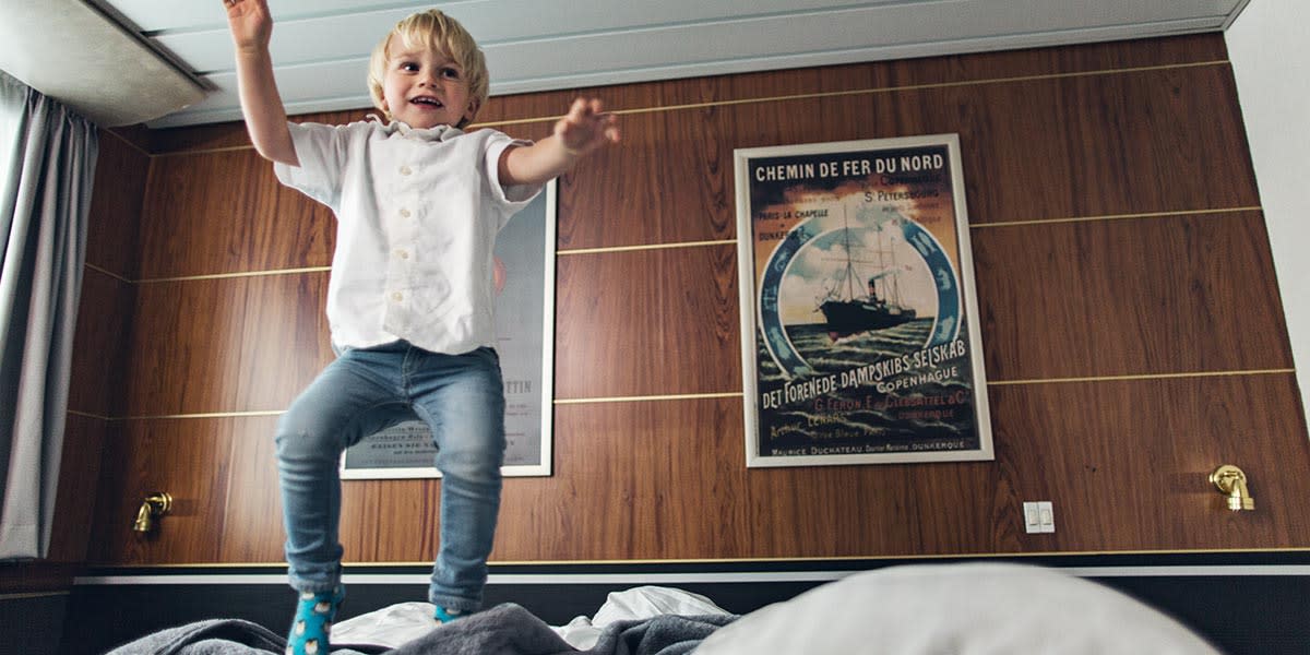 Mały chłopiec skacze na dużym łóżku w kabinie na promie