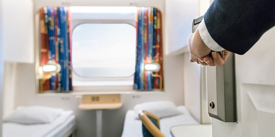 A hand opening the door to a standard sea view cabin.
