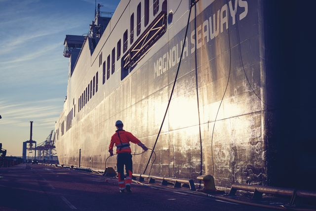 A DFDS Freight employee ensuring Magnolia Seaways is properly secured during an early-morning docking