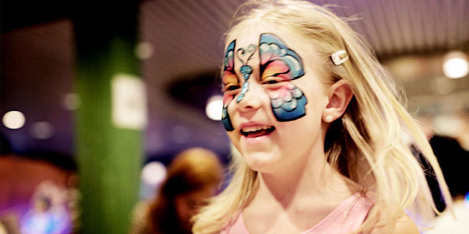 A little girl running around with face paint on. 