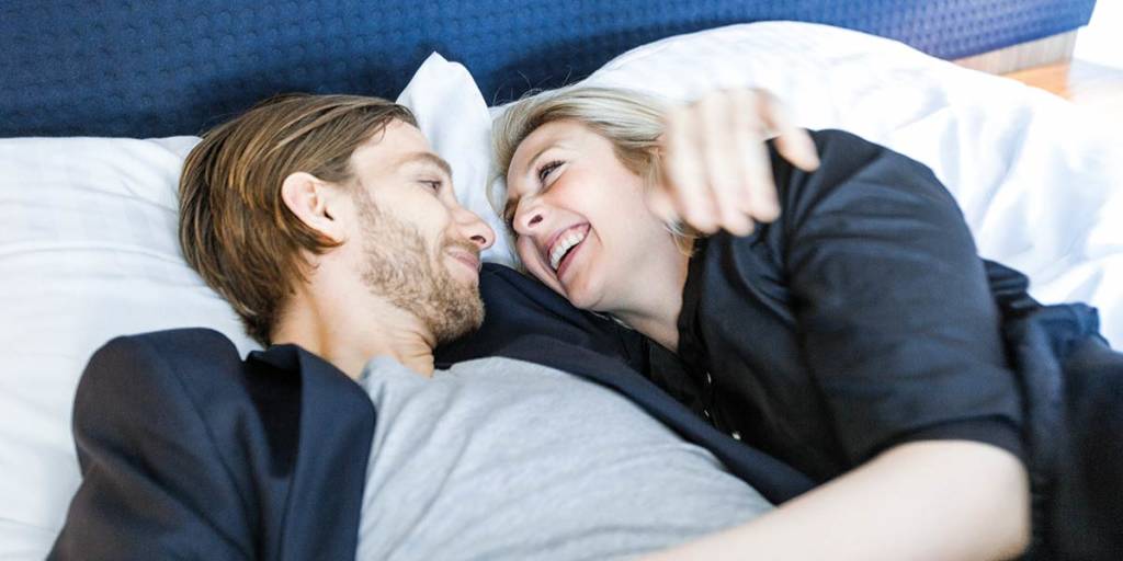 Uśmiechnięta para leży na łóżku w kabinie