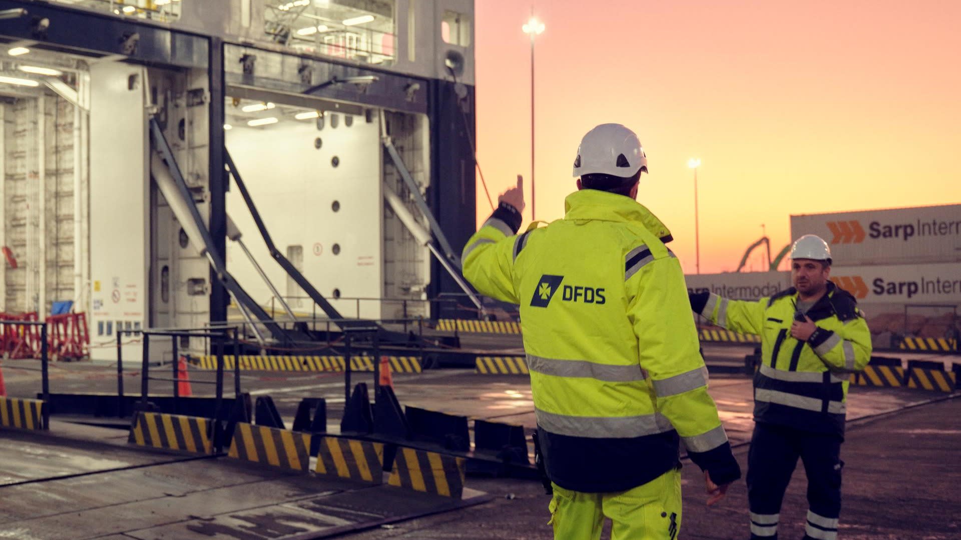 Purpose & Strategy page, About section, Pillar E Great place to work - two DFDS harbour workers with reflective safety workwear, standing at the entrance of a docked vessel 73997-DFDS Pendik Istanbul 01 2023 062 1702067001185