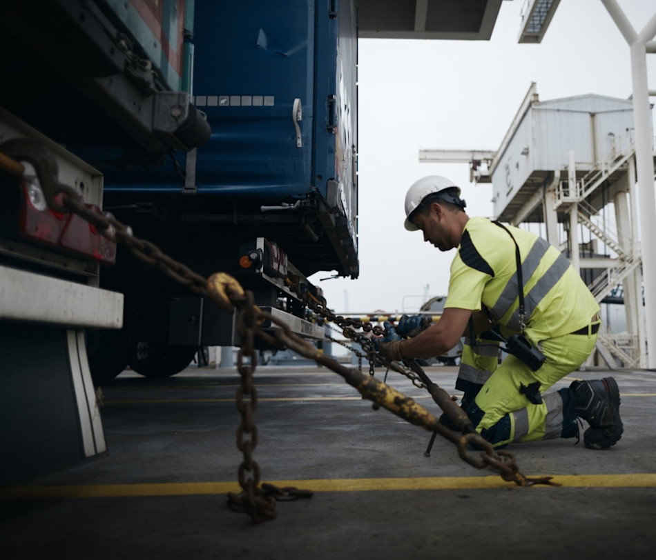 Photo of a DFDS Logistics worker tying down a truck to the ground