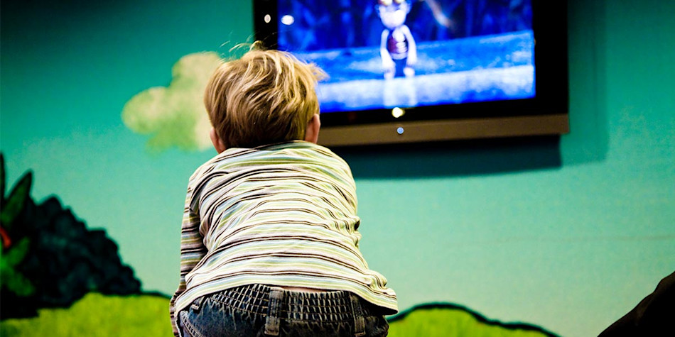 A little boy watching a cartoon television program in the kids club.