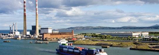 A DFDS Logistics ship sailing past a power plant