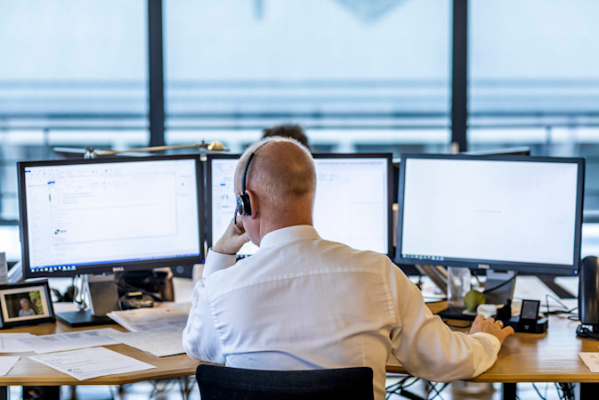 A DSDS employee sitting on an office desk, wearing a headset