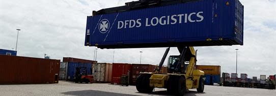 DFDS Logistics loader in a shipyard hoisting a DFDS container
