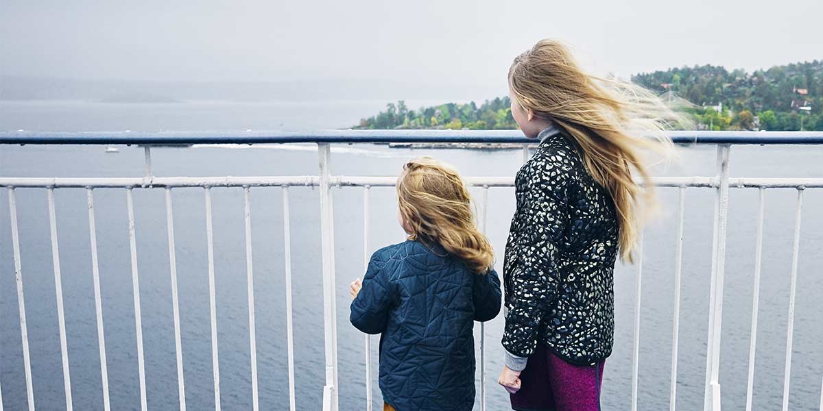 To barn ser ut på sjøen fra dekk