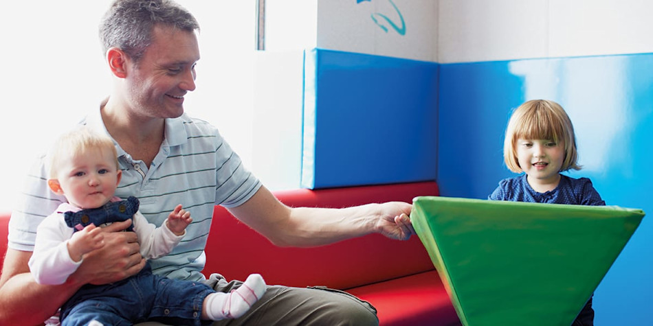 Little girl playing while father holds younger sibling onboard Newhaven- Dieppe ferry.