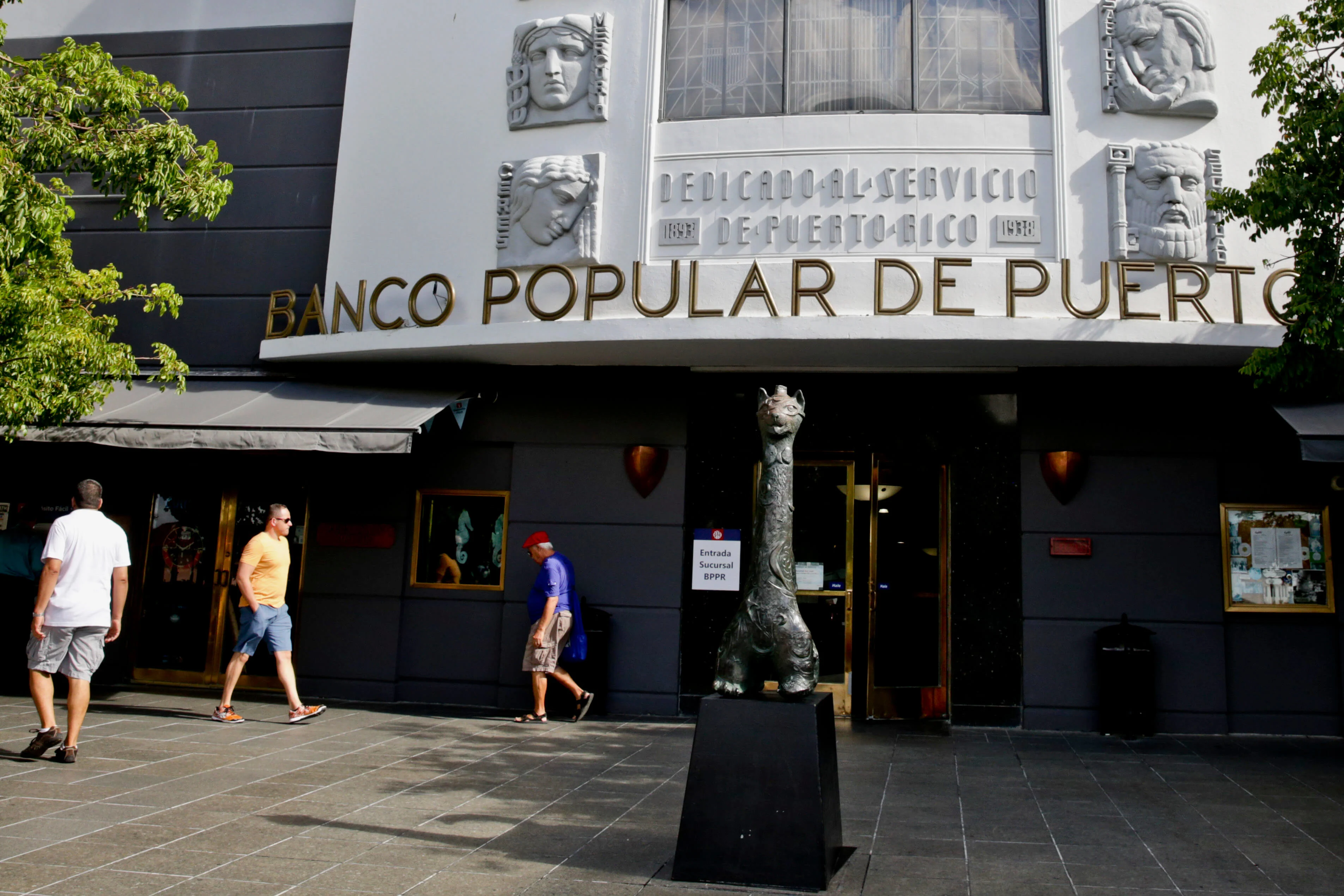 Fachada del Banco Popular de Puerto Rico con letrero dorado y relieves decorativos, personas caminando frente al edificio. 

Derick E. Hingle/Bloomberg via Getty Images