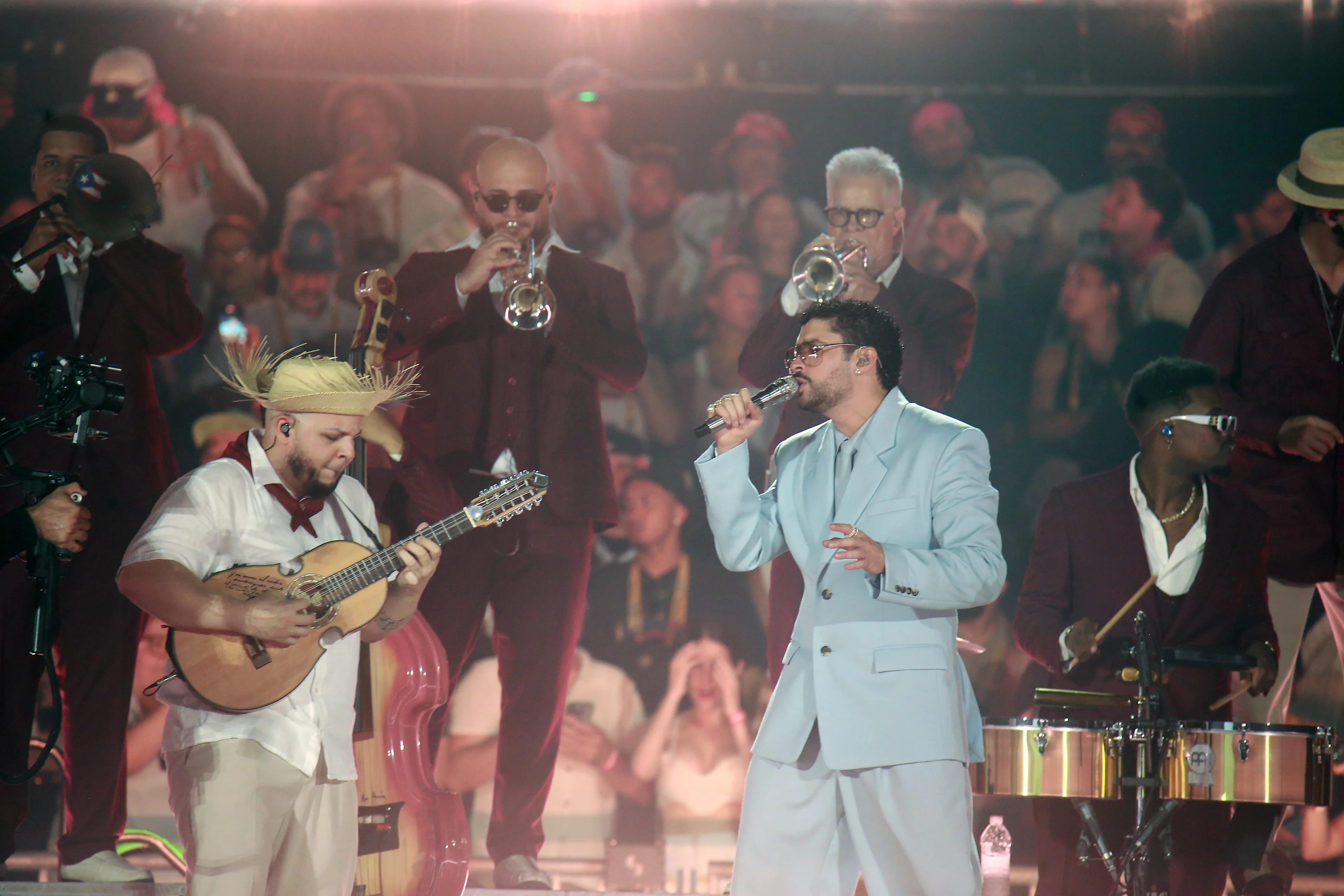 Músicos en tarima con cuatro, trompetas y timbales en presentación con público de fondo y luces de escenario.
Foto: Gladys Vega/Getty Image