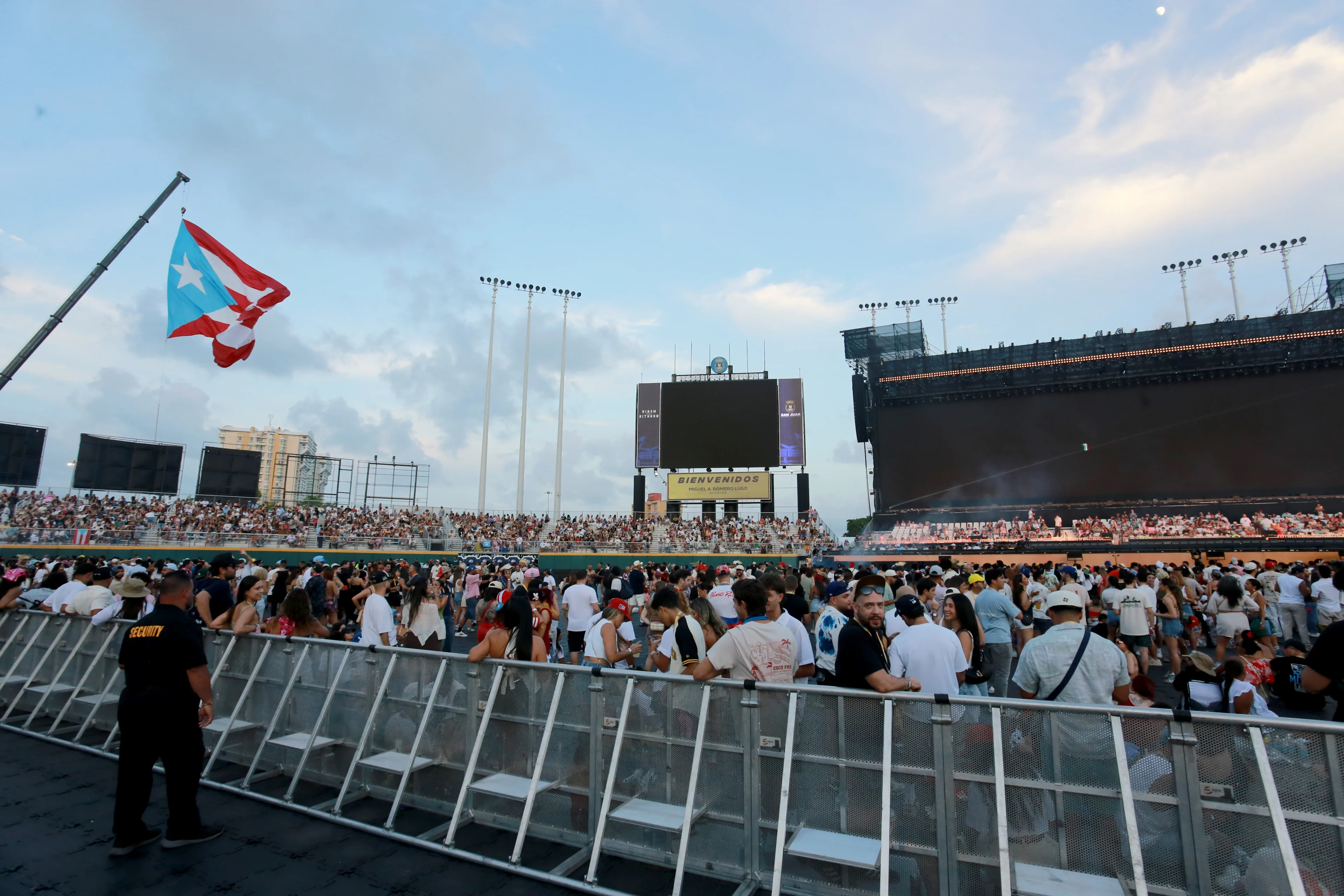 Multitud en estadio con bandera de Puerto Rico ondeando, pantallas y gradas llenas al atardecer.
Gladys Vega/Getty Images