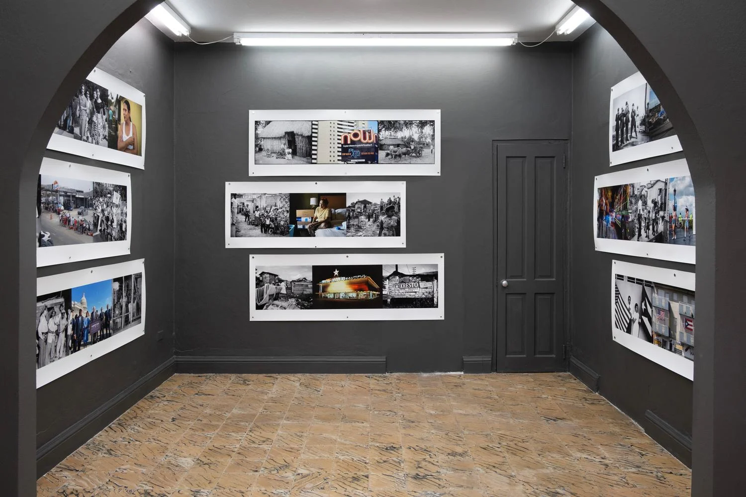 Sala de exhibición con paredes grises y fotografías en blanco y negro con detalles en color sobre Puerto Rico.