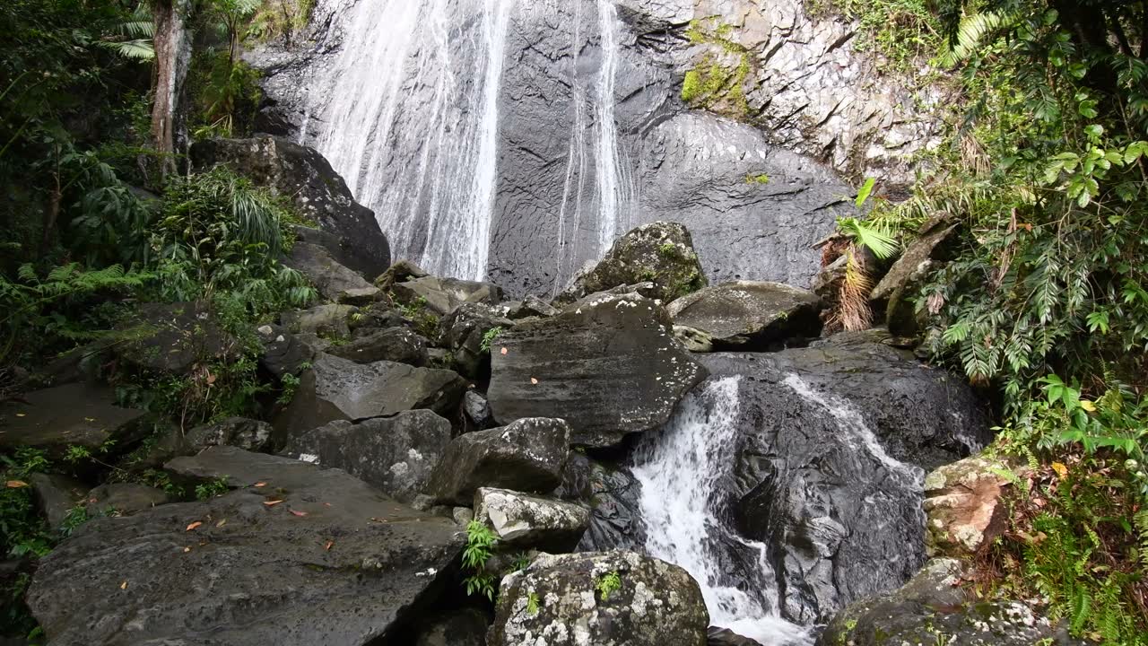 La cascada La Coca cae entre rocas y vegetación.