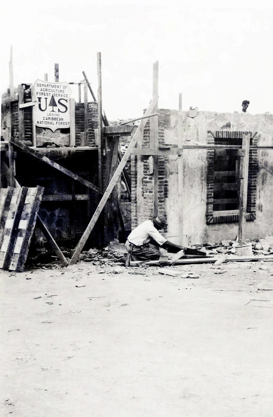 Un obrero trabaja en la construcción de la puerta de acceso al bosque, junto a un letrero del Servicio Forestal, en 1938.