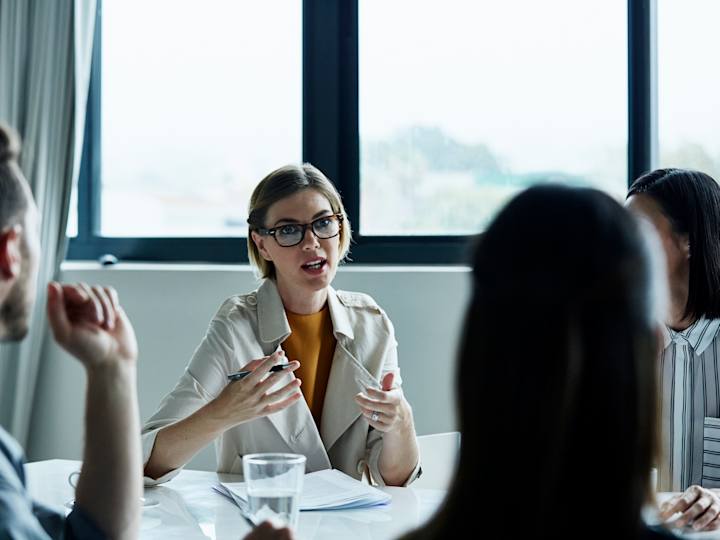 Person sidder til møde med kollegaer og forklarer