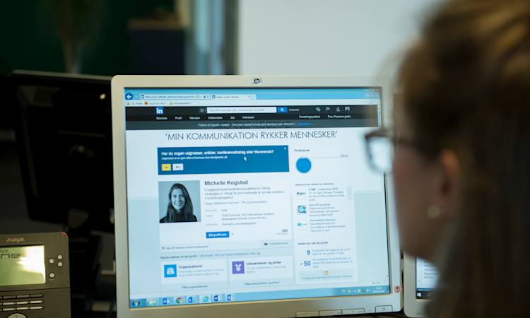 Person sidder foran computerskærm, hvorpå der vises en LinkedIn profil