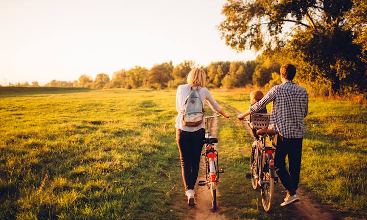 Familie på ferie, der går med cykler i naturen