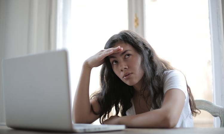 Kvinde sidder og kigger skeptisk ved sin pc