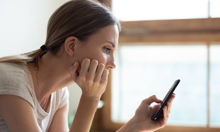 Person ser nedtrykt på sin mobiltelefon