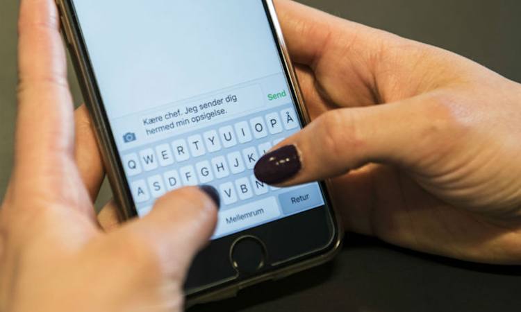 Person skriver en opsigelse i en sms på mobiltelefon