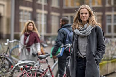 Ung kvinde står på gaden foran nogle cykler