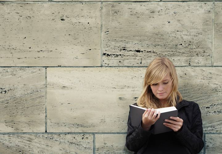 Jobsøgende står op af mur og kigger i bog