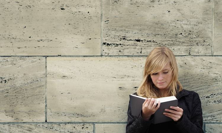 Jobsøgende står op af mur og kigger i bog