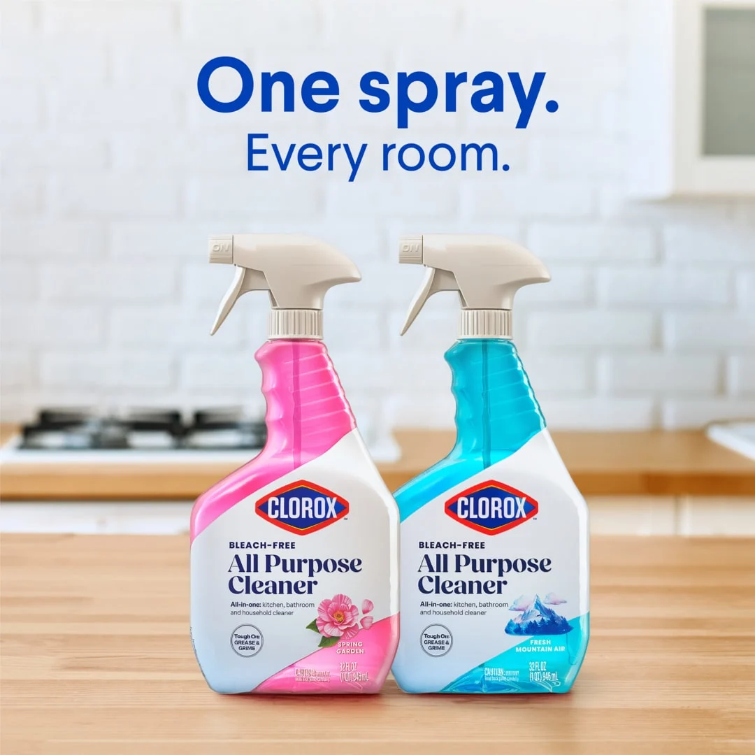 Botellas de limpiador multiusos con aromas a jardín en primavera y aire fresco de montaña sobre un mostrador de cocina con las palabras "Un spray, cada habitación".