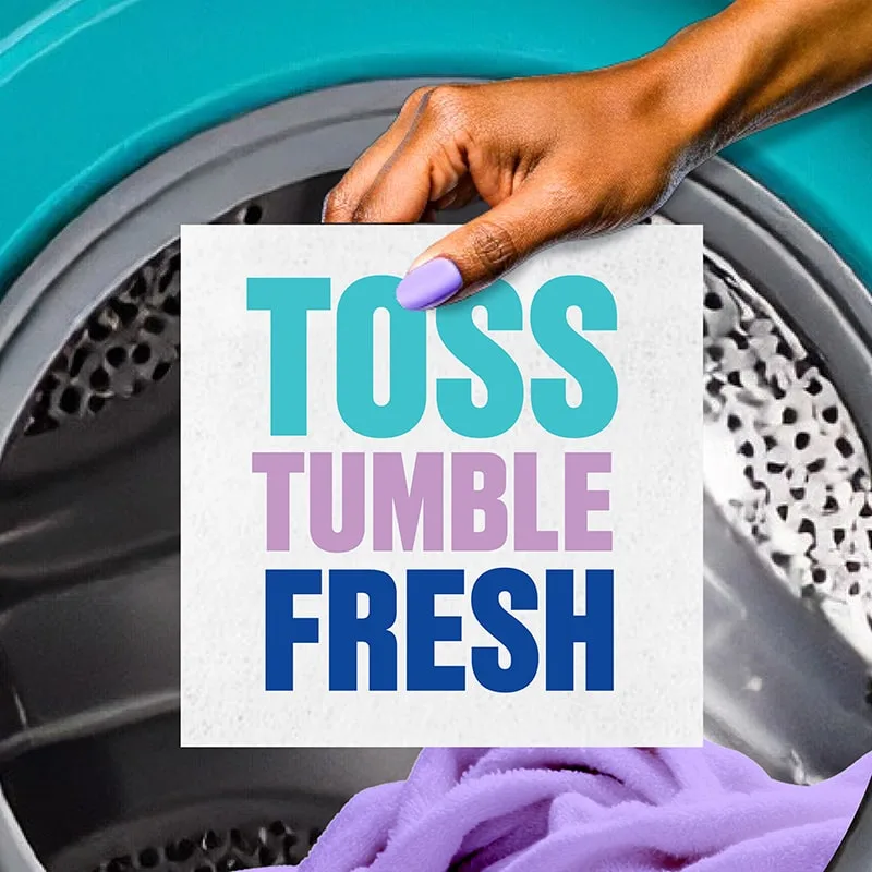 The words "Toss, Tumble, Fresh" in printed on a washer sheet being held by a hand in fron of a front-load dryer