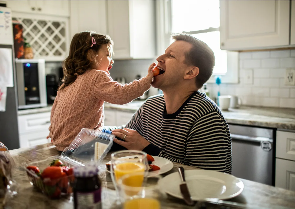 un hombre y una niña comiendo en la cocina