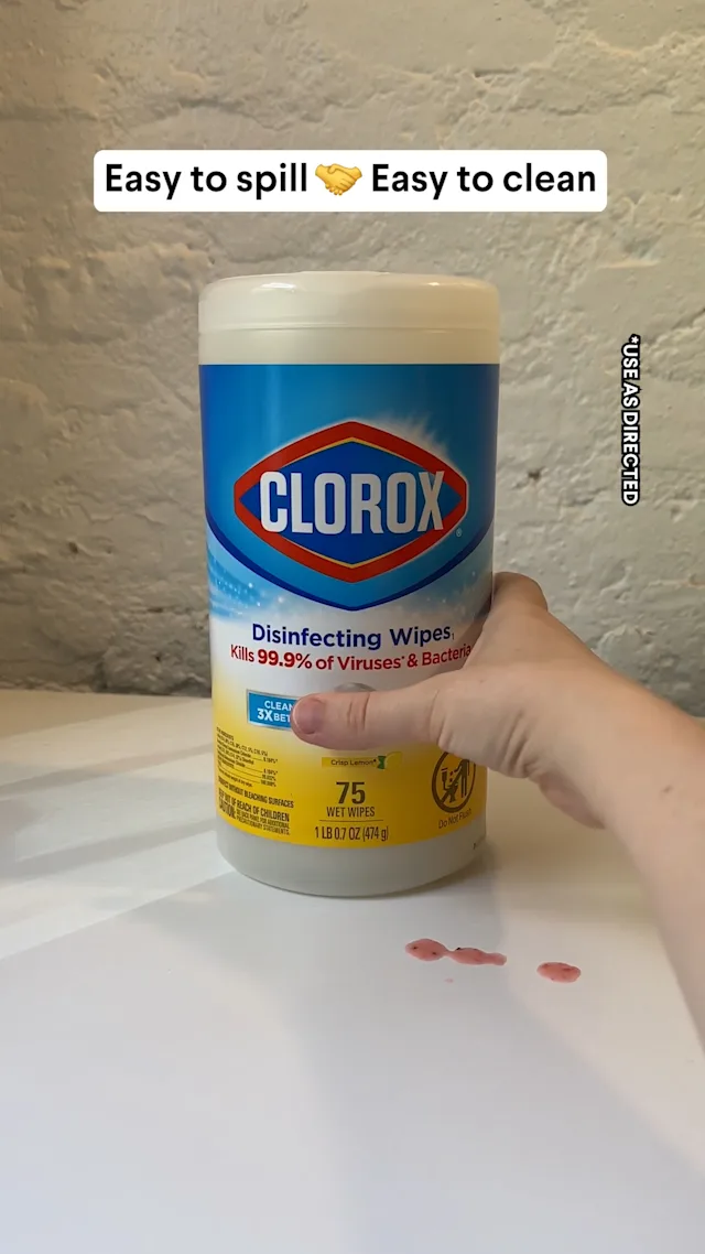 Hand holding a canister of Clorox Disinfecting Wipes over a kitchen counter