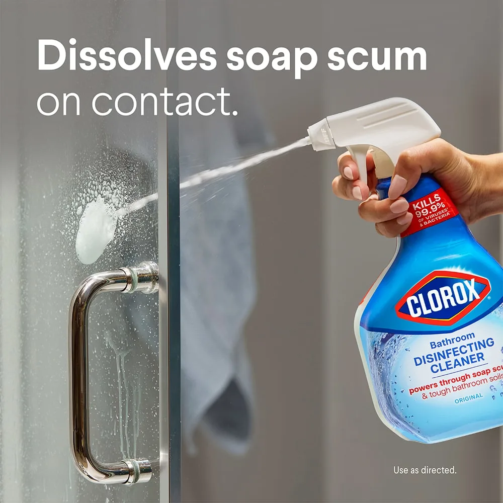 Hand spraying Disinfecting Bathroom Cleaner on a glass shower door with the words Dissolved soap scum on contact