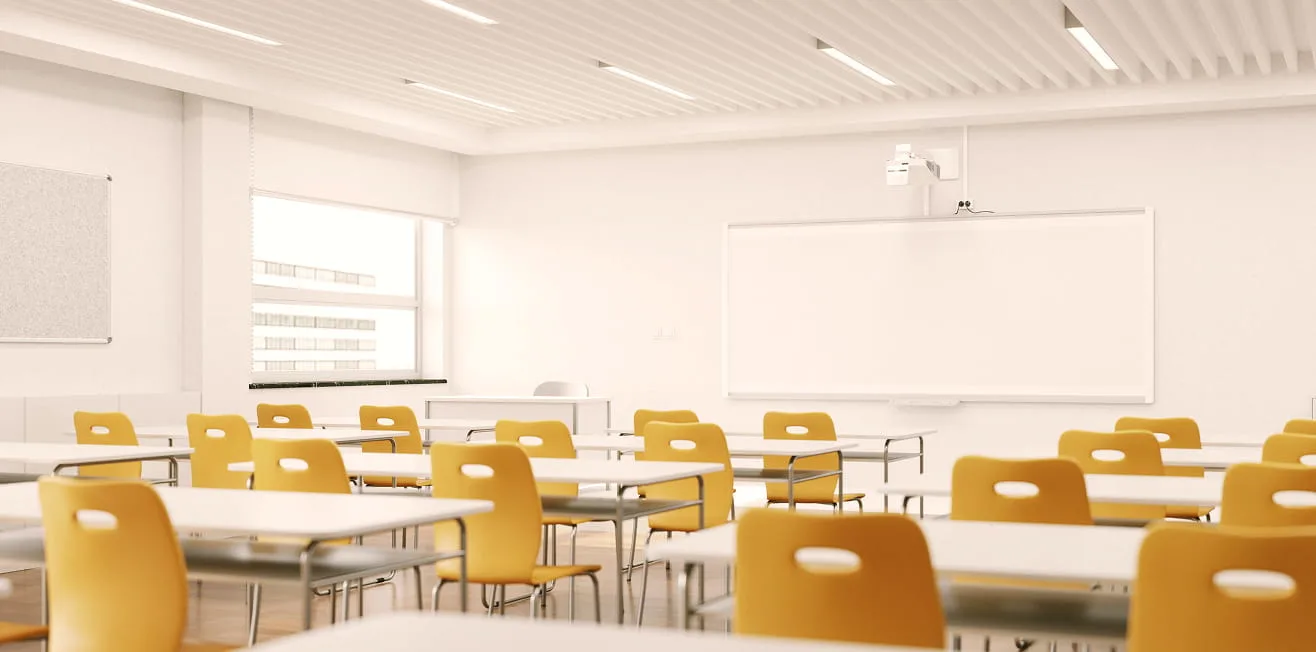 Empty classroom with yellow chairs, white desks, whiteboard, projector and natural light.