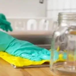 gloved hand wipes a wood countertop