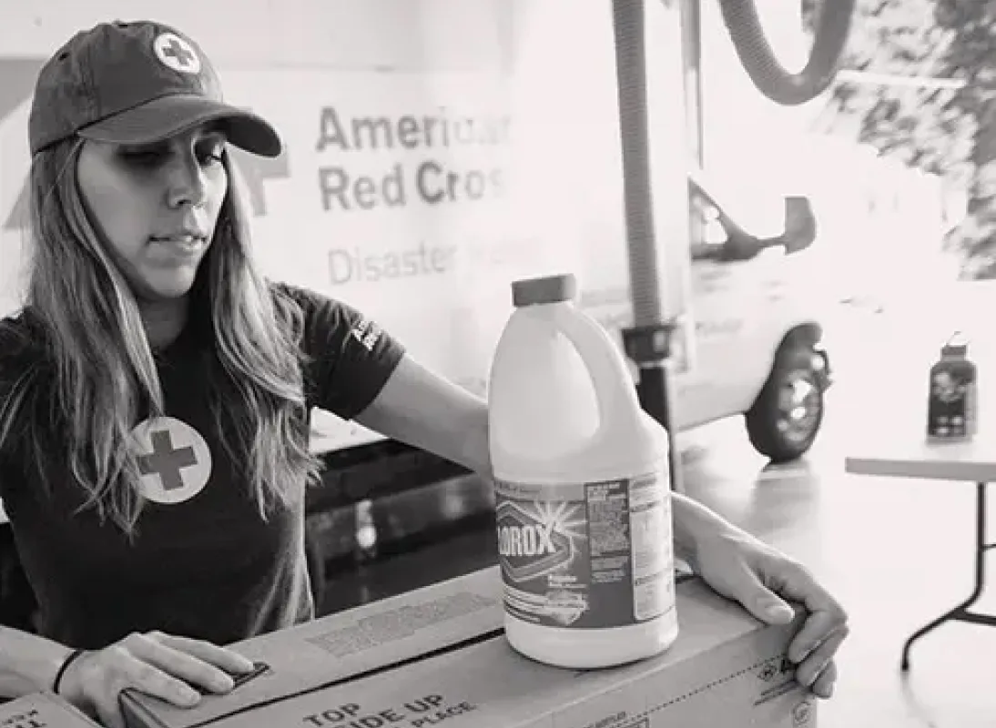 trabajadora de la cruz roja con una botella de blanqueador clorox